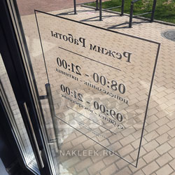 Входная табличка с режимом работы на стекле двери